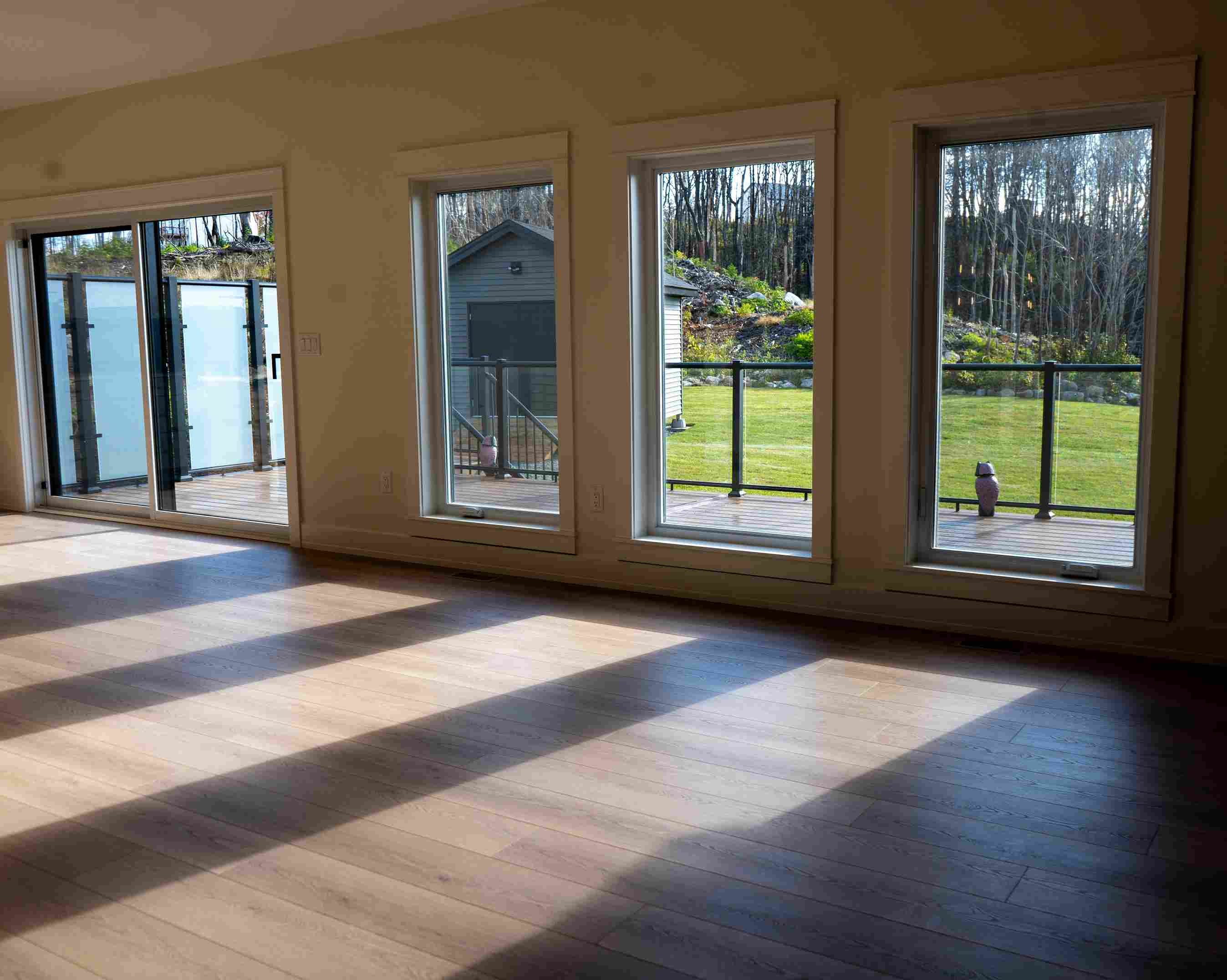 Interior of a bright accessory dwelling unit featuring hardwood floors and large windows overlooking a deck