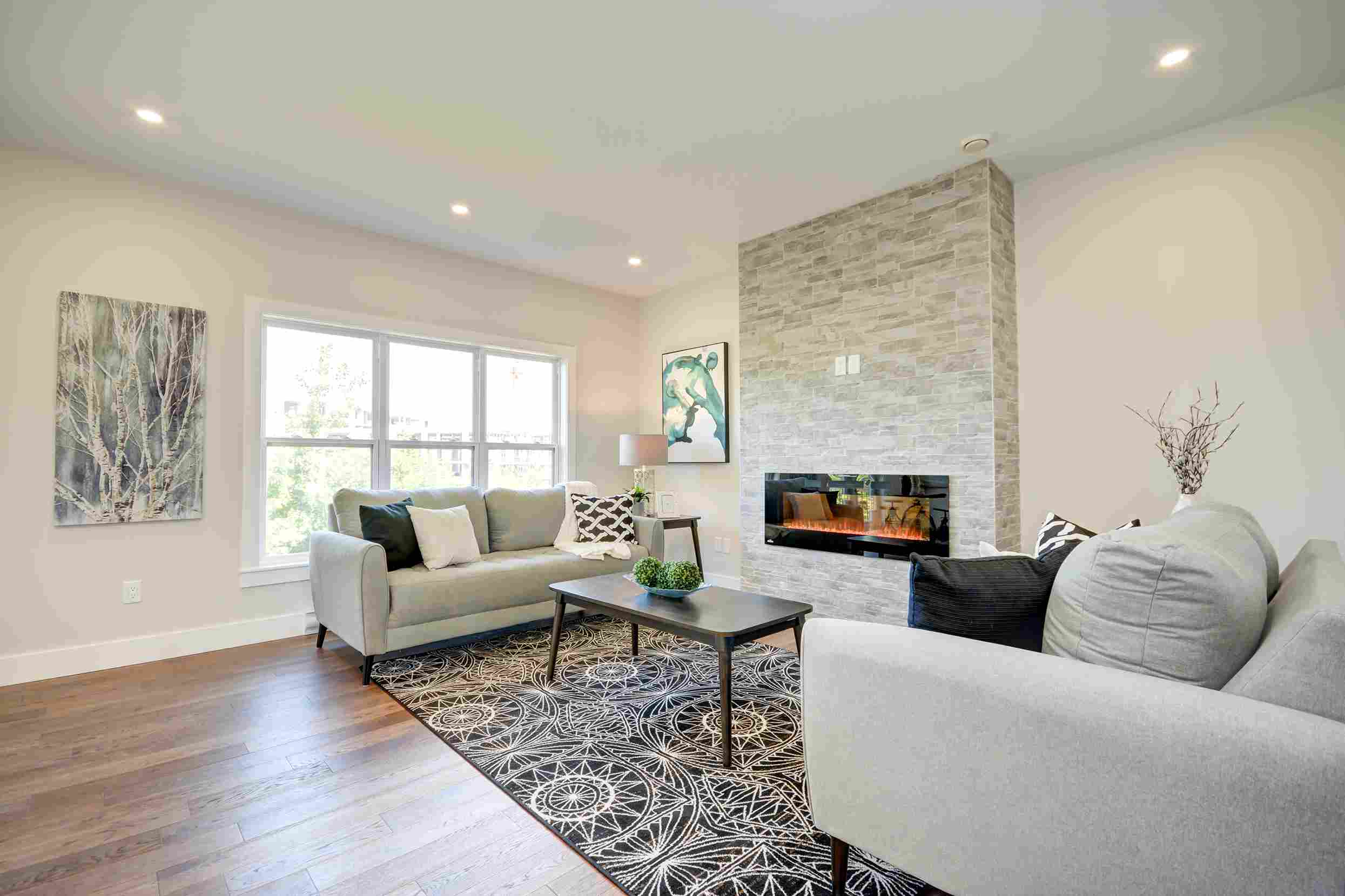 Contemporary living room with floor-to-ceiling stone fireplace and hardwood floors - custom home interior by Signature Homes Halifax