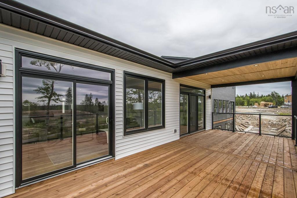 Spacious wooden deck with covered patio area on a Halifax duplex construction project, featuring black-framed sliding glass doors and modern outdoor living space