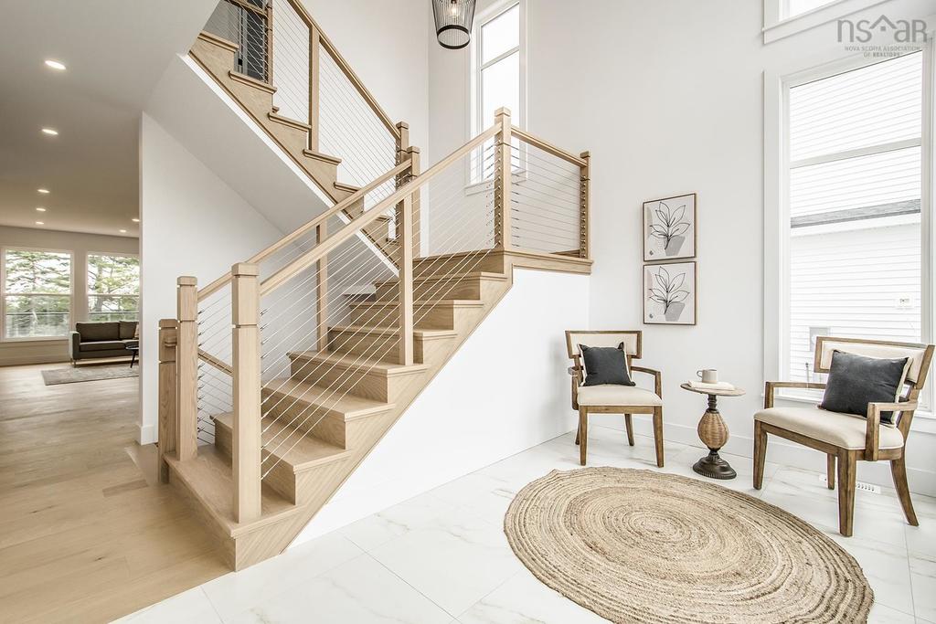 Contemporary interior staircase with natural wood steps and cable railings in a new build duplex, showcasing modern minimalist design and bright open foyer
