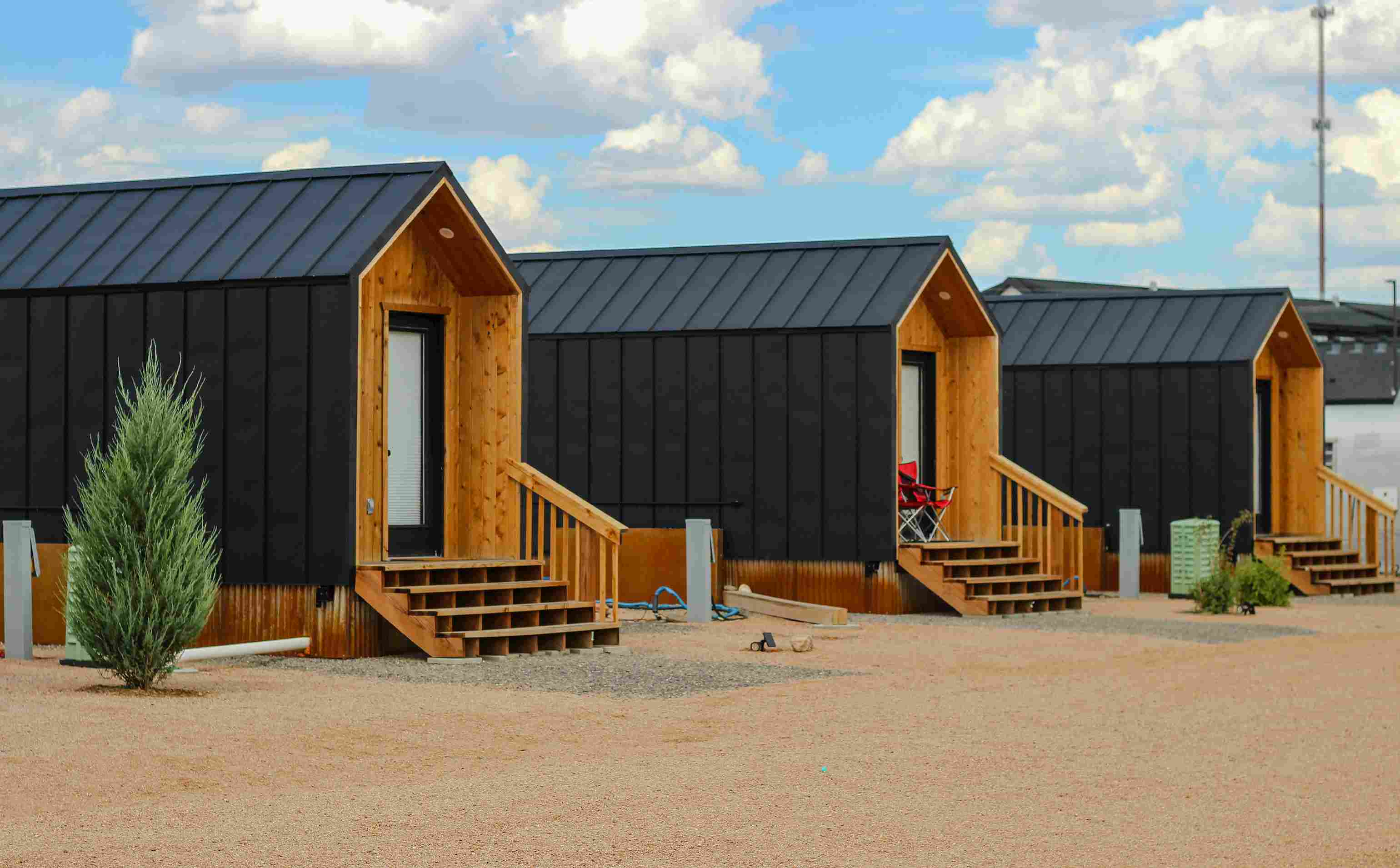 Row of tiny homes on foundation with black metal siding and wood accents
