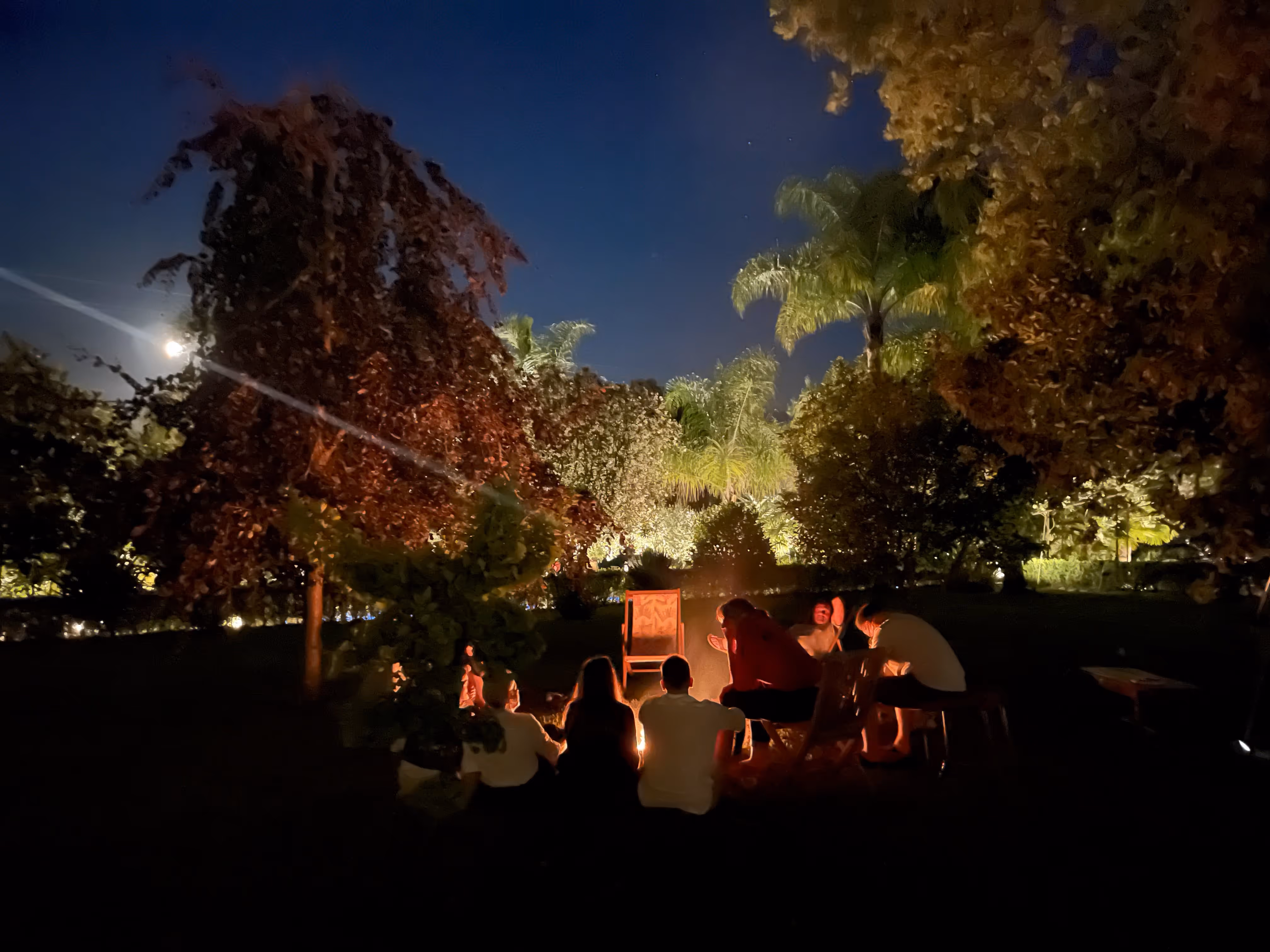 Grupo reunido à volta da fogueira no jardim sob a lua cheia na Casa da Seara