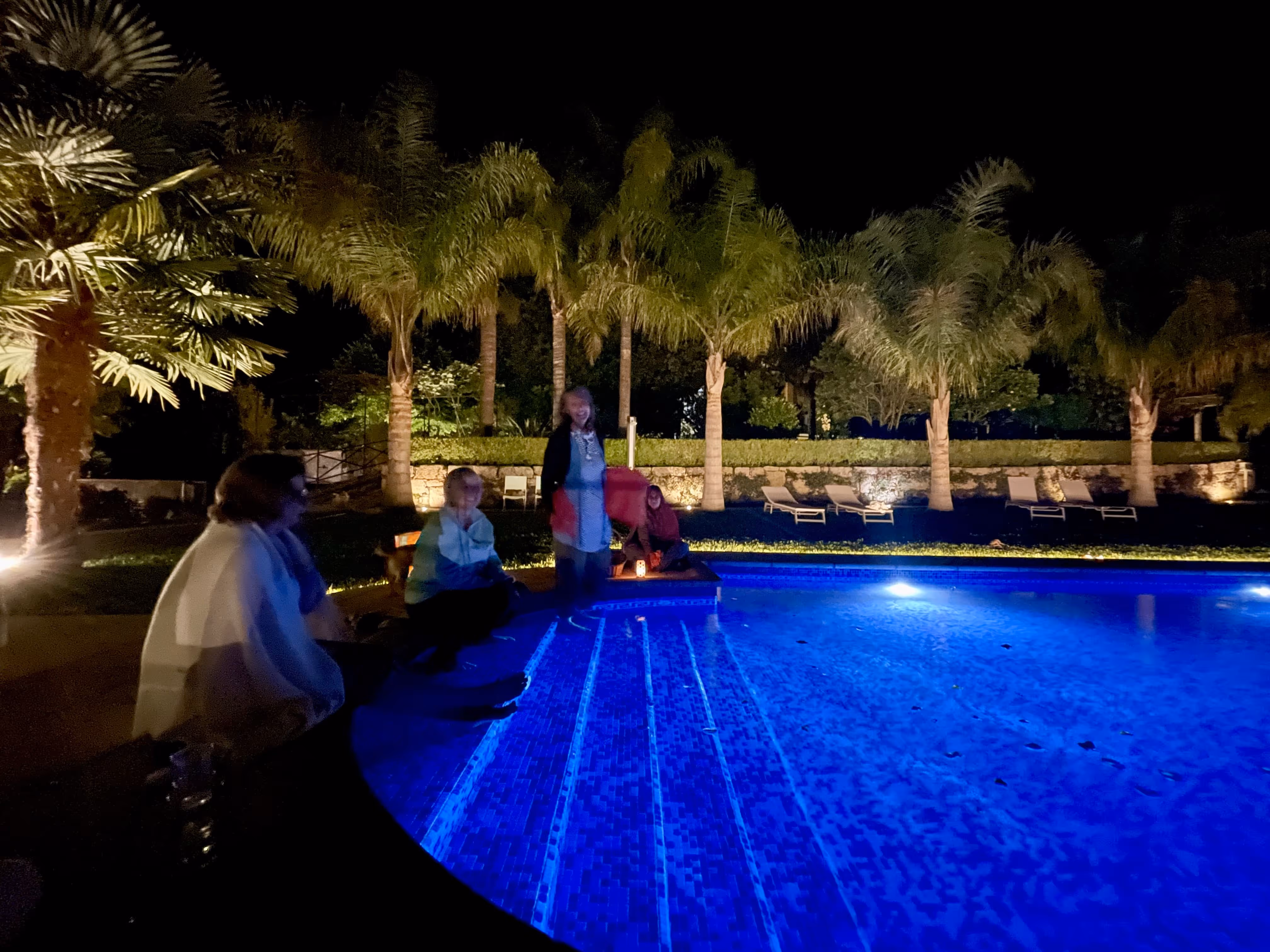Pessoas reunidas à noite junto à piscina iluminada na Casa da Seara