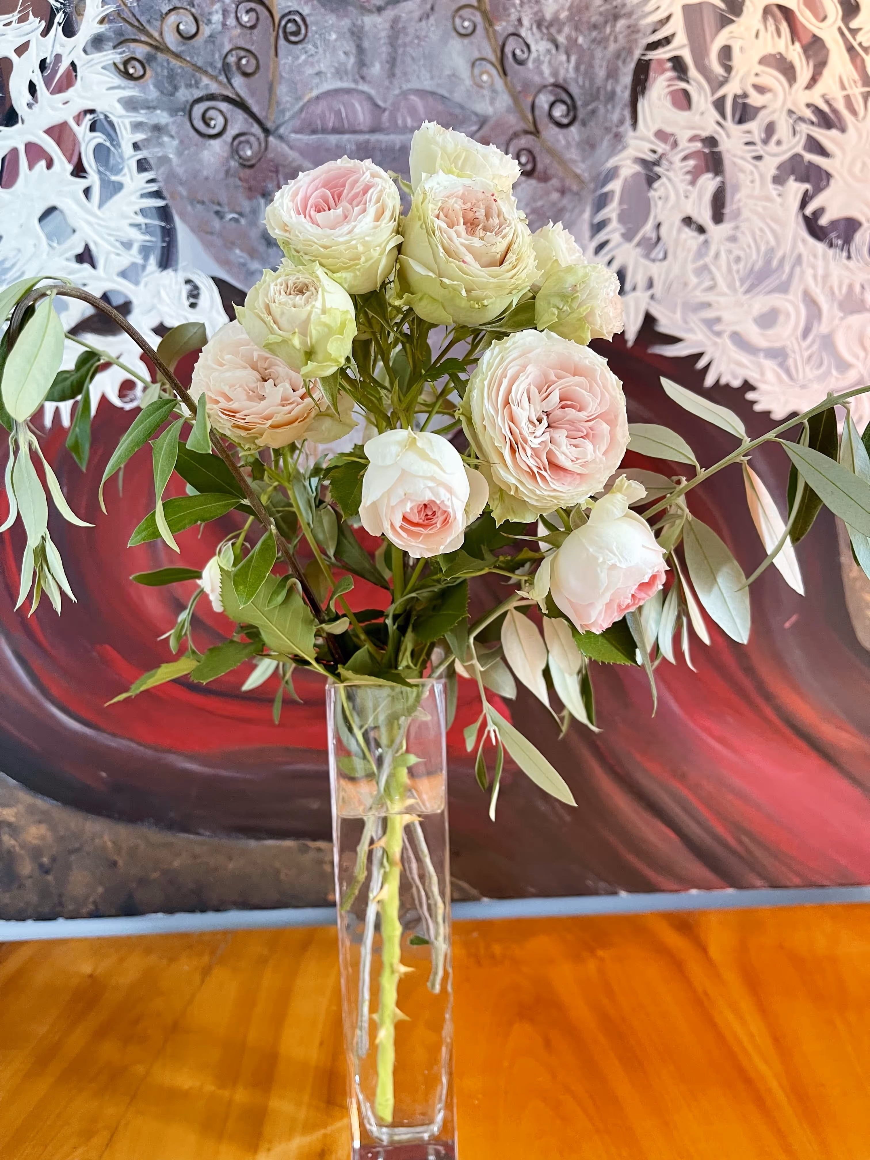 Vaso com rosas cor-de-rosa à frente de uma pintura artística na Casa da Seara