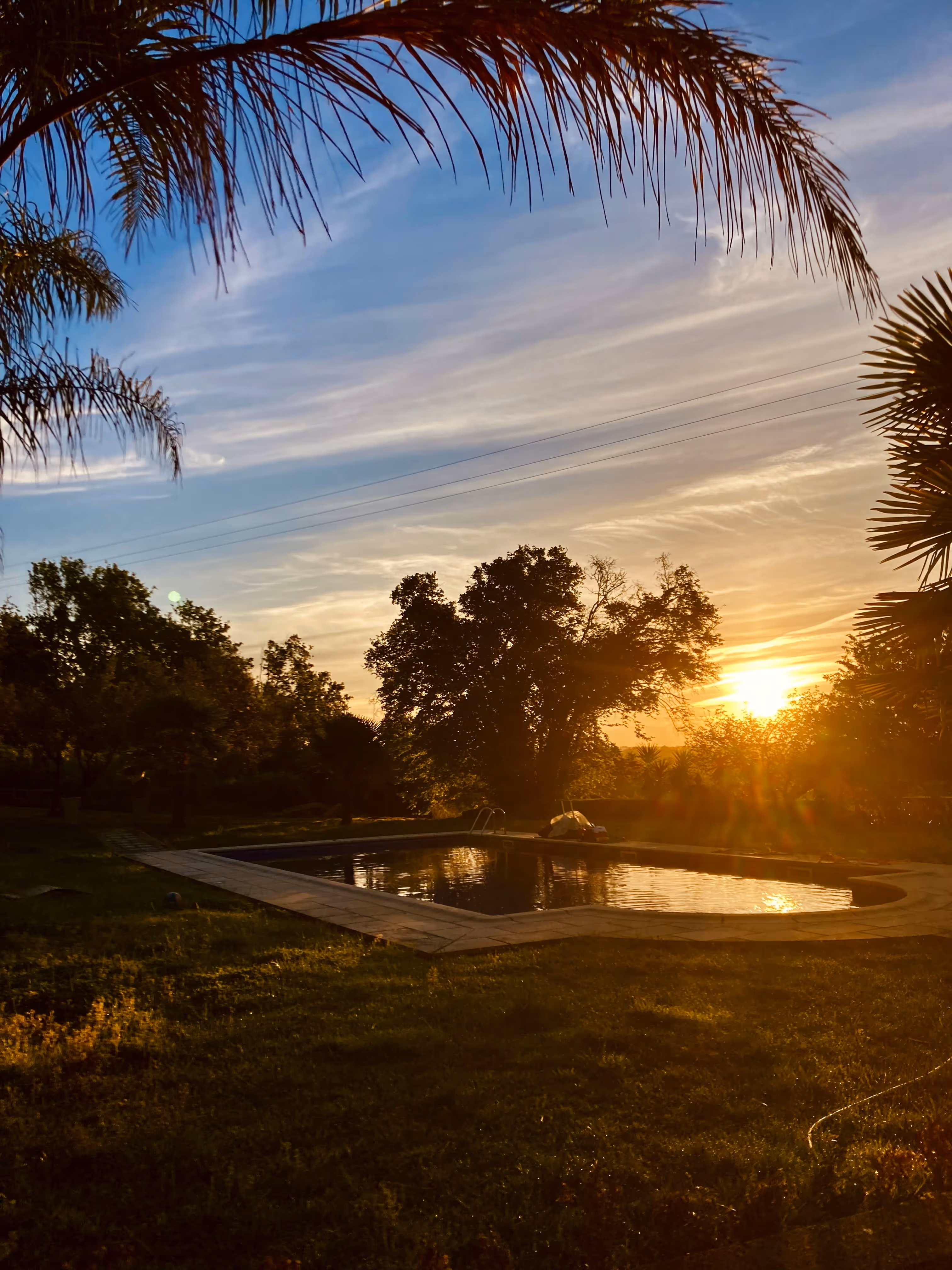 Piscina rodeada de natureza com pôr do sol dourado na Casa da Seara