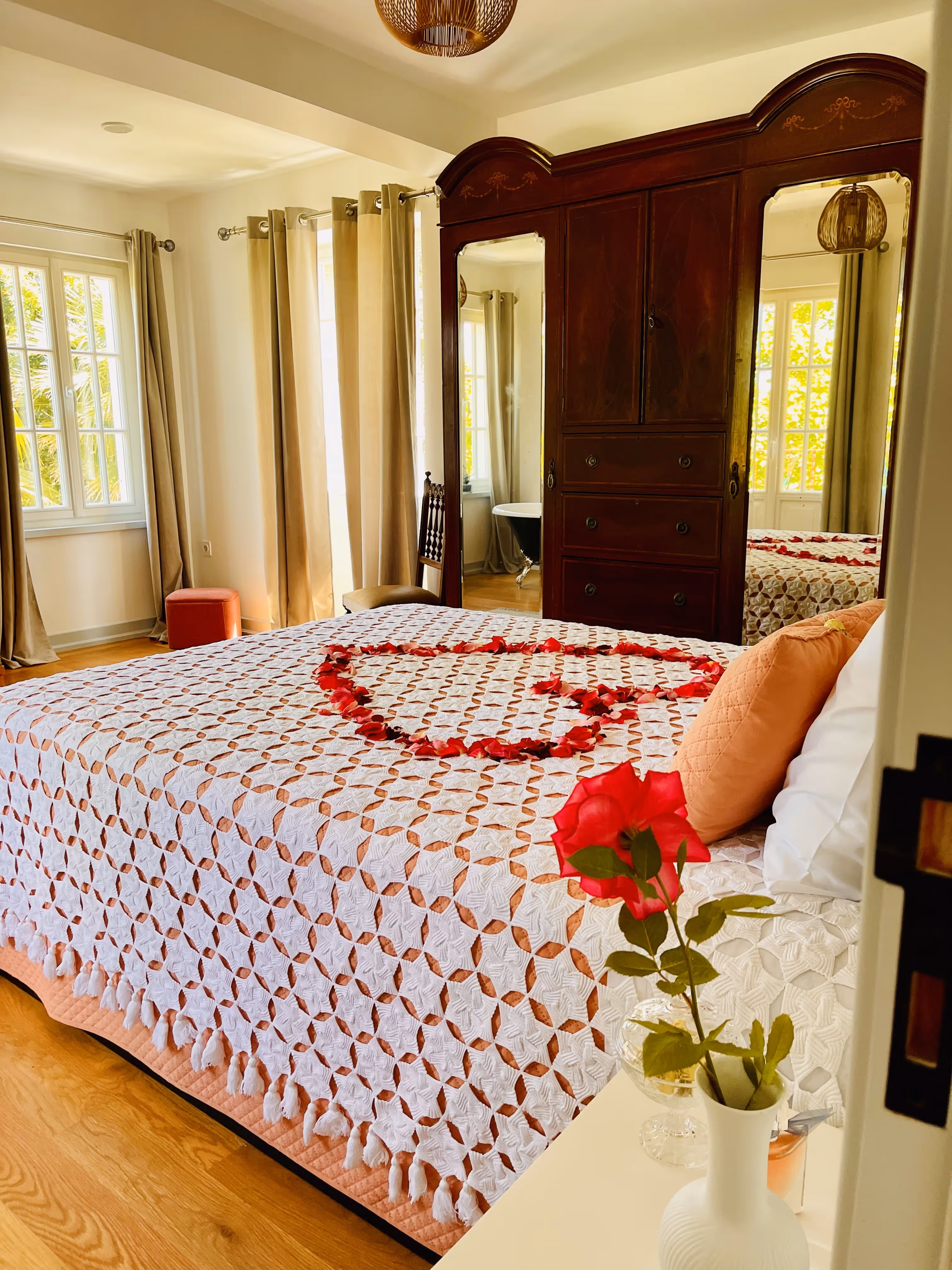 Quarto luminoso com cama decorada com pétalas em forma de coração na Casa da Seara