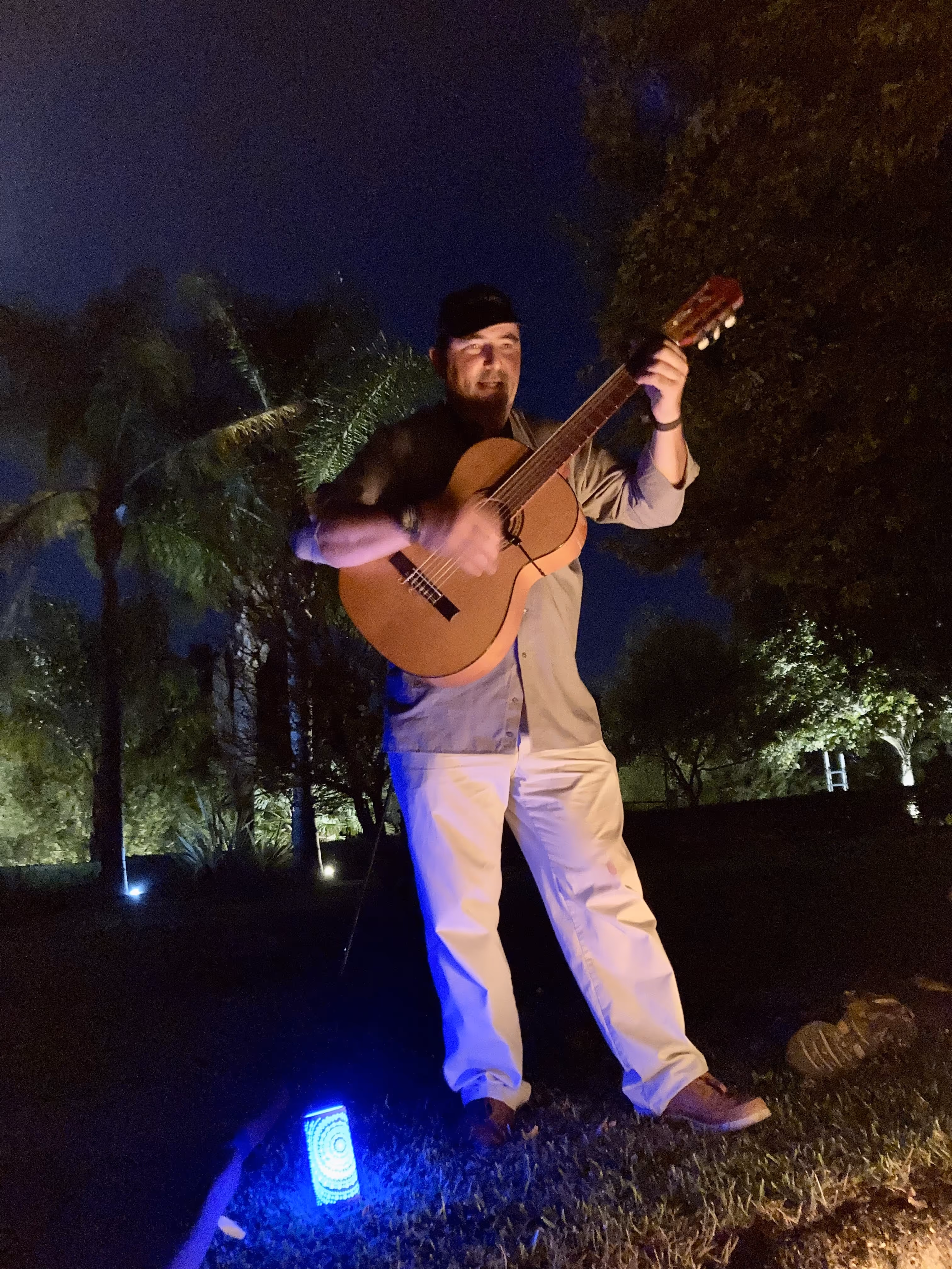 Músico a tocar violão à noite no jardim iluminado da Casa da Seara