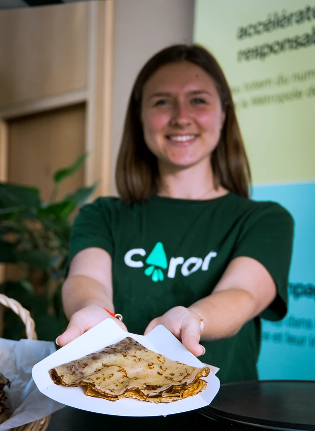Équipière Carot' tendant une crêpe lors d'une animation en entreprise