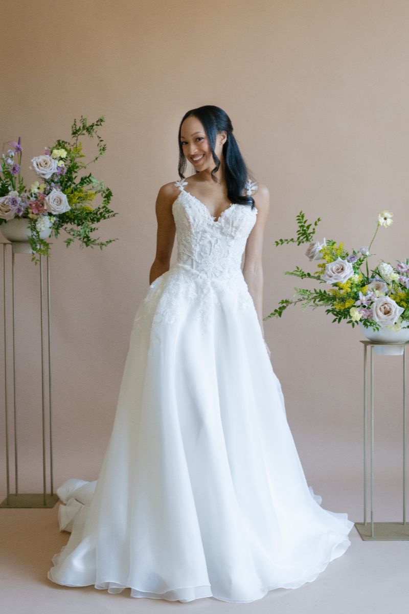 A-line gown with V-neck, spaghetti straps, floral appliquéd bodice, and a flowing skirt.