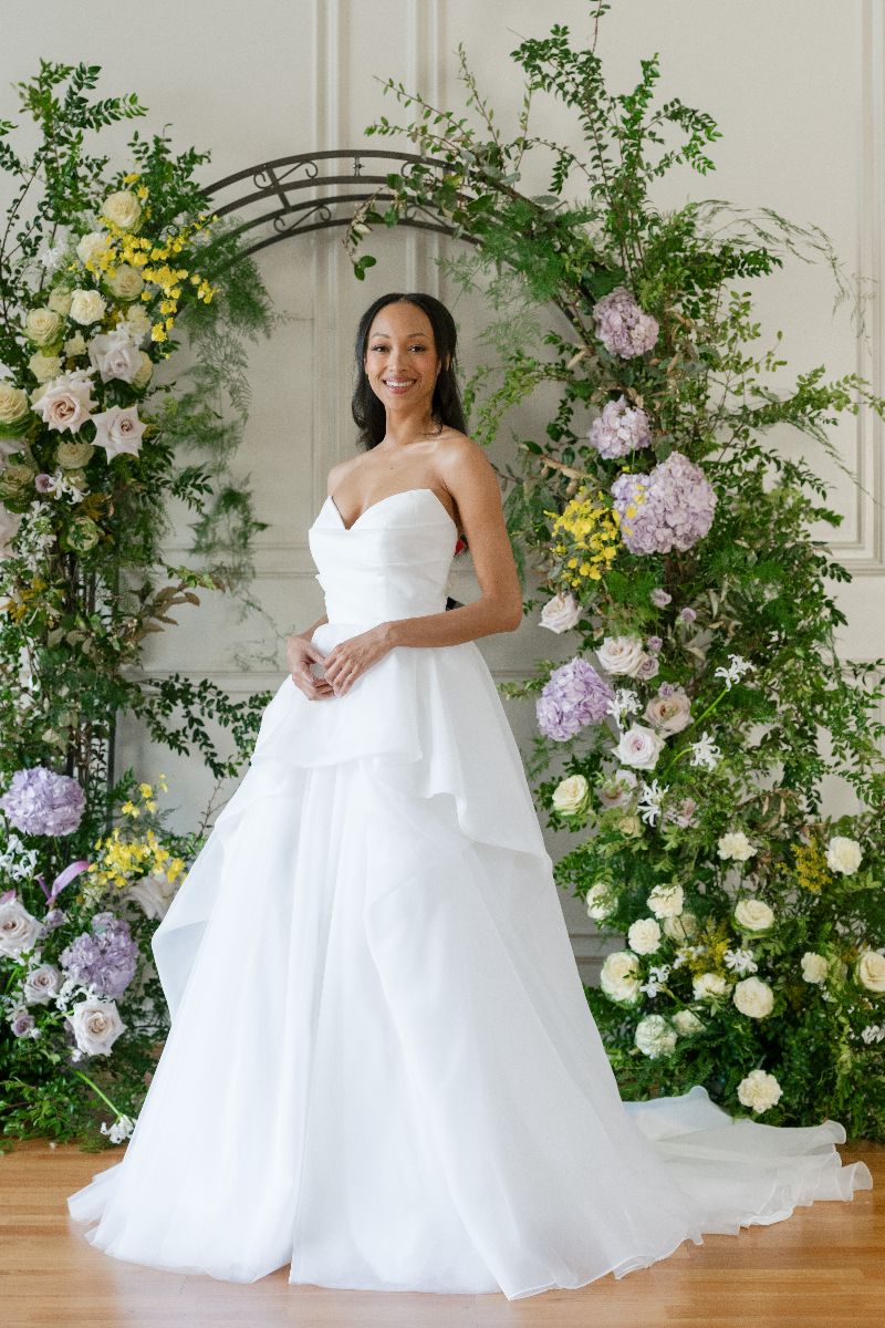 The flowing tiered tulle skirt creates a dreamy, romantic silhouette for the modern bride