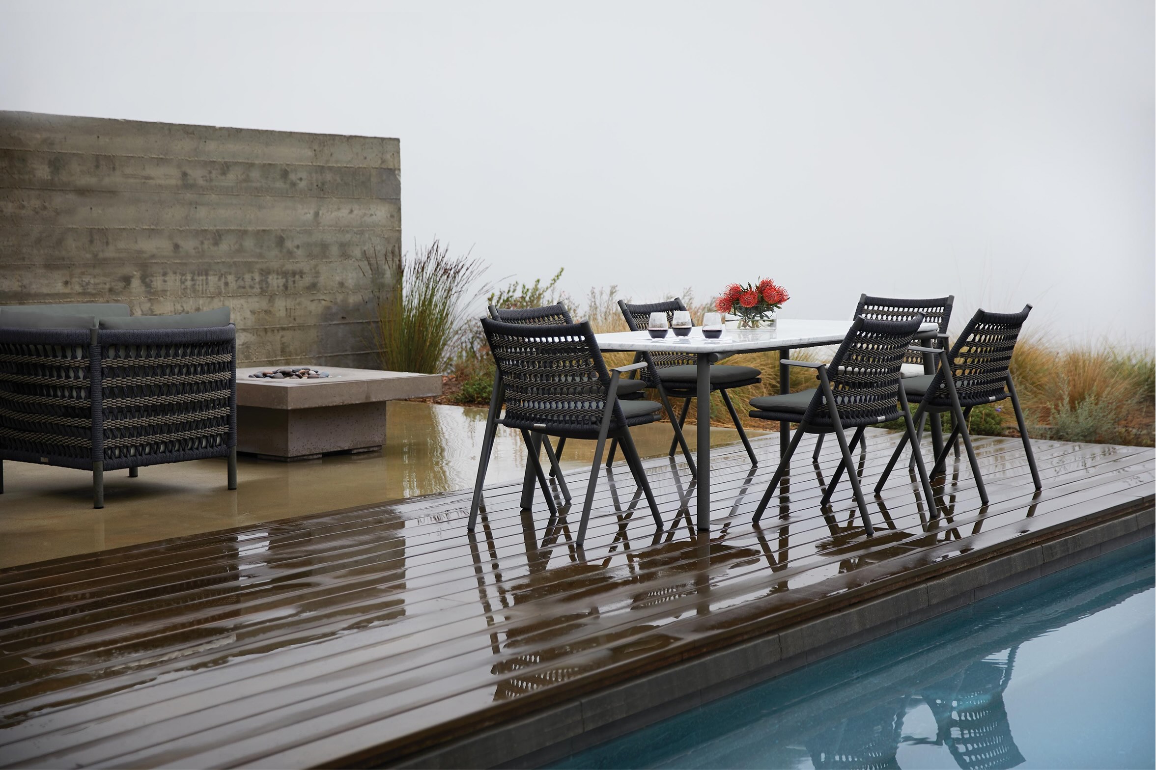 A rainy deck overlooking the ocean next to a pool