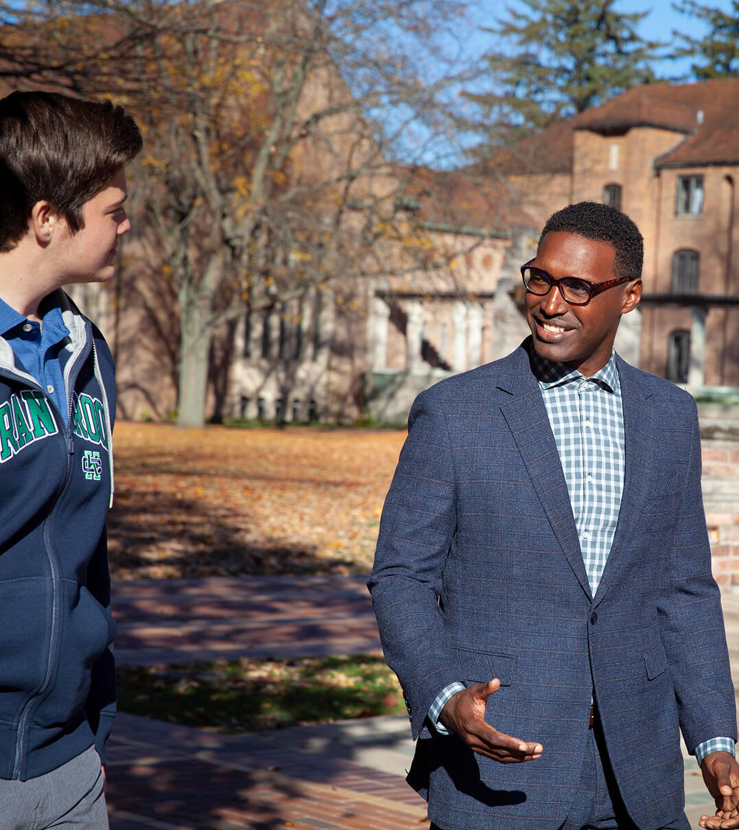 A Cranbrook Schools teacher talking to a student while walking across campus.