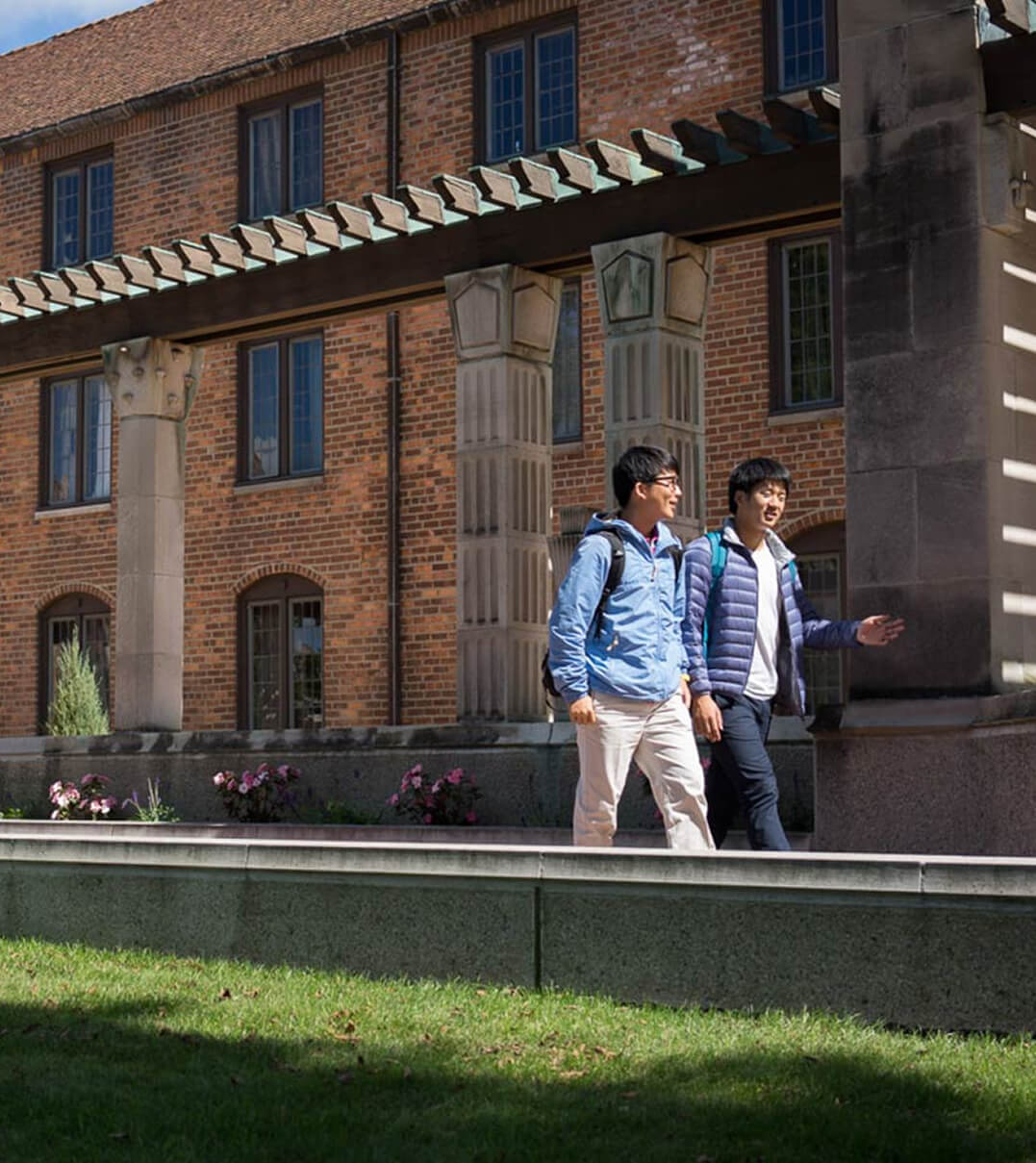 Two Cranbrook Schools students walking across campus and talking.
