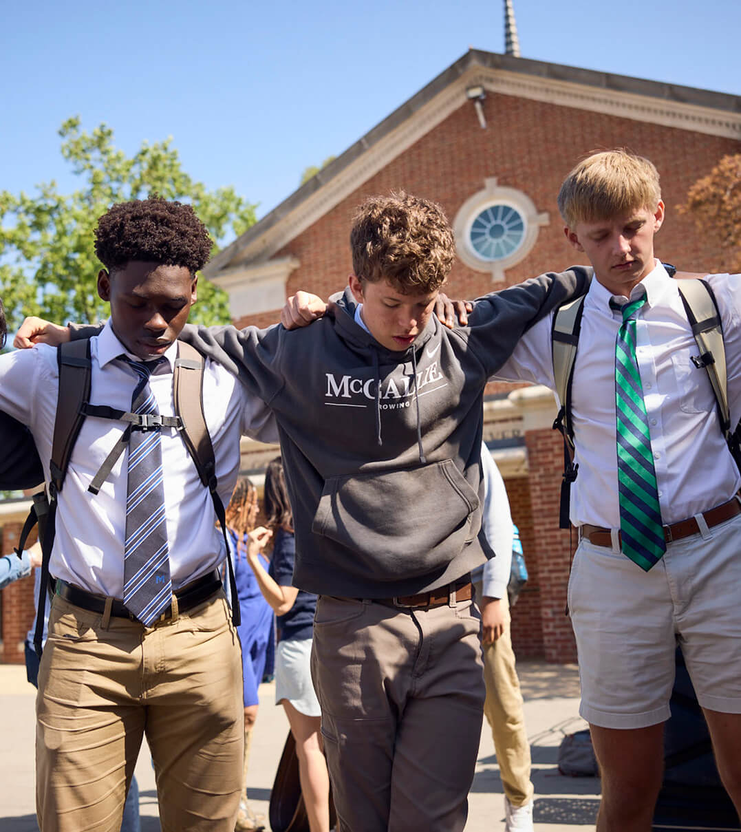 McCallie students standing arm-in-arm and bowing their heads in a moment of silence.