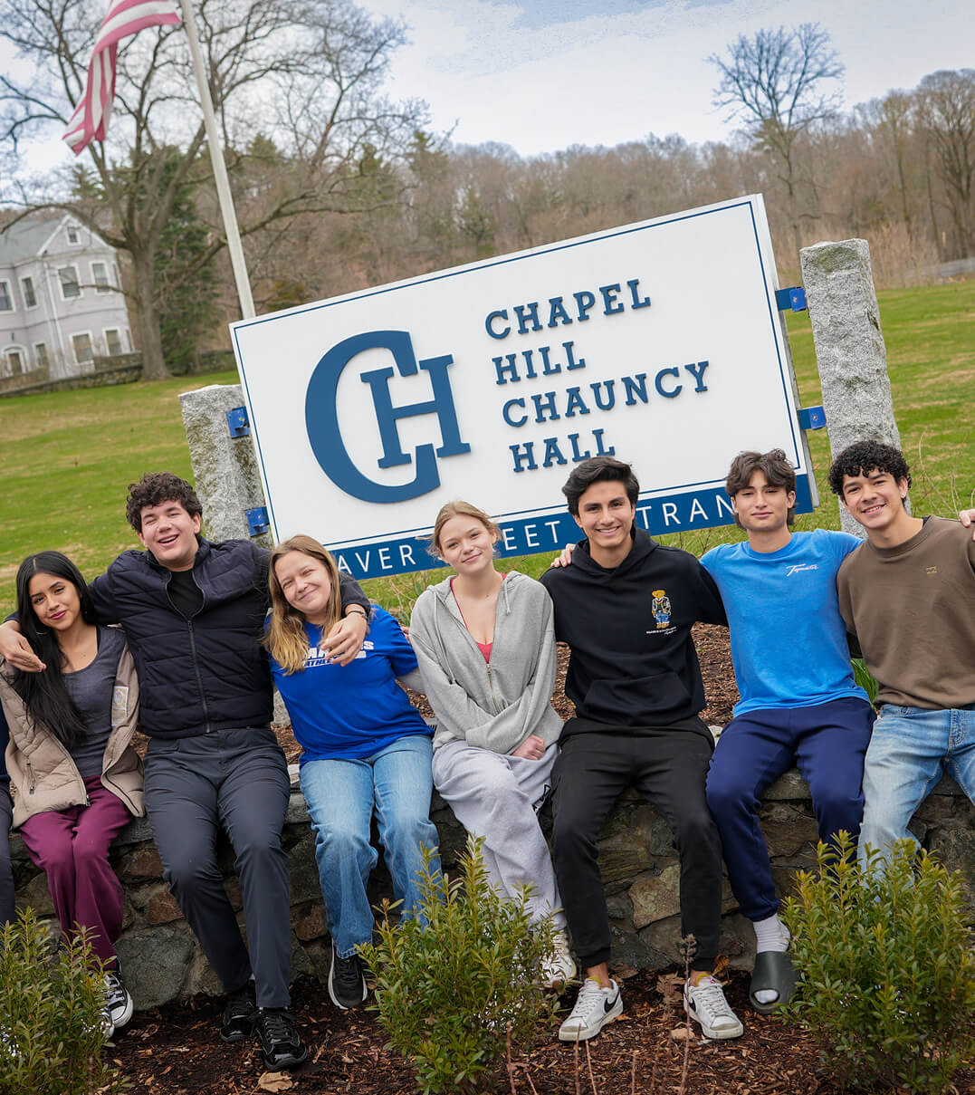 Chapel Hill-Chauncy Hall students posing for a photo in front of the school sign.