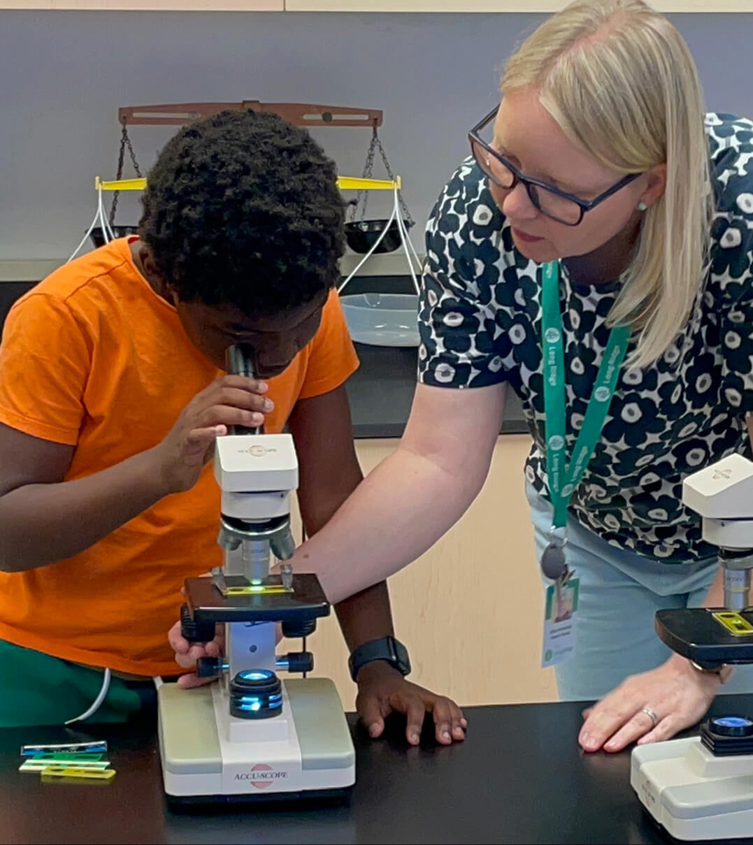 A Long Ridge teacher oversees a student's use of the microscope.
