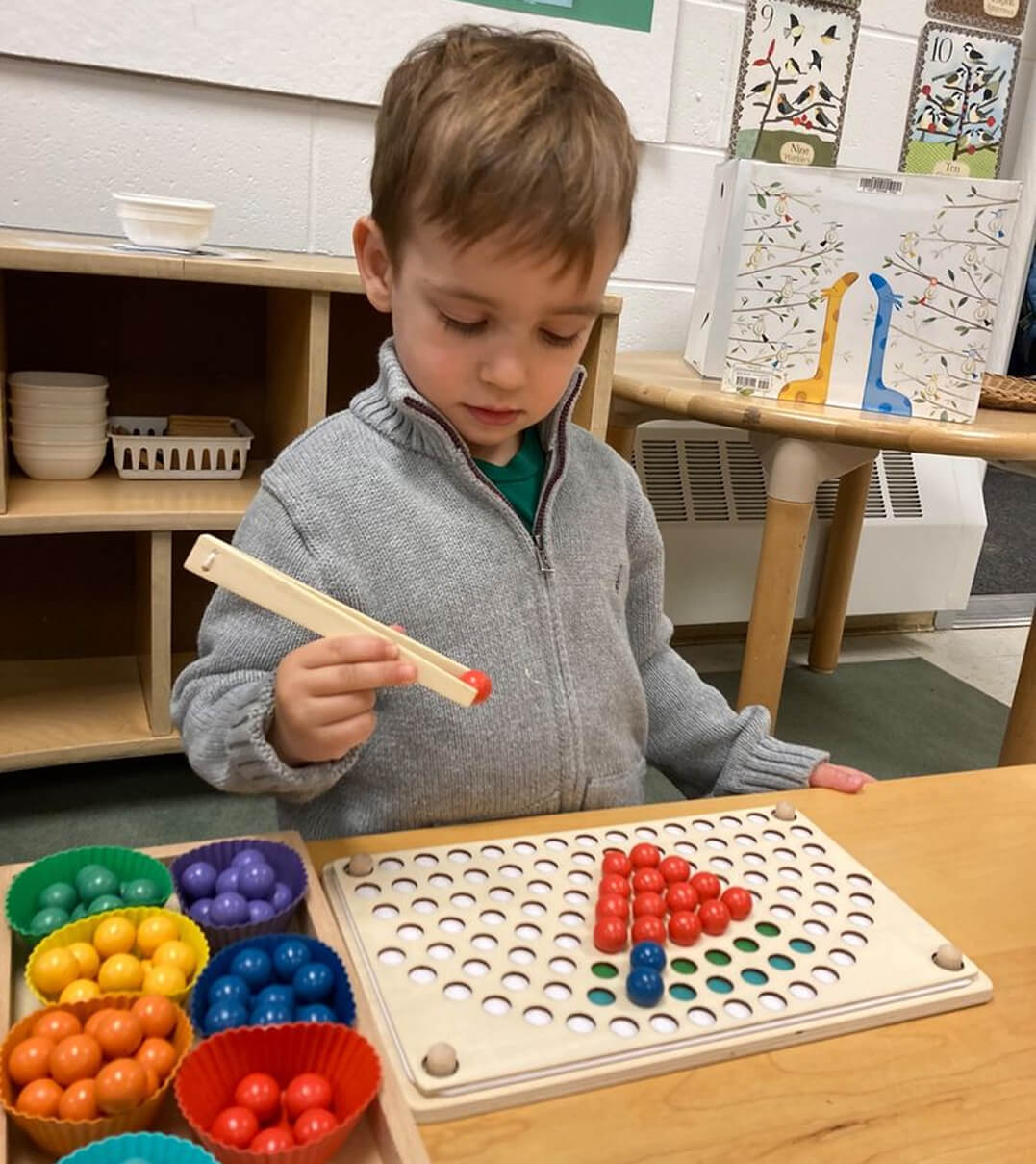 A Long Ridge student uses tongs to sorts different colored marbles.