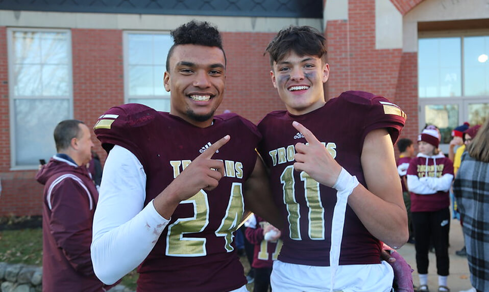 Two Thornton Academy football players holding their pointer finger up to represent being number 1.