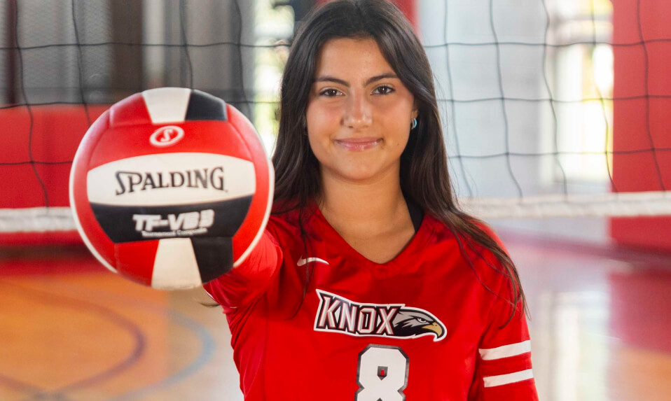 A Knox School volleyball player holding the volleyball up toward the camera.