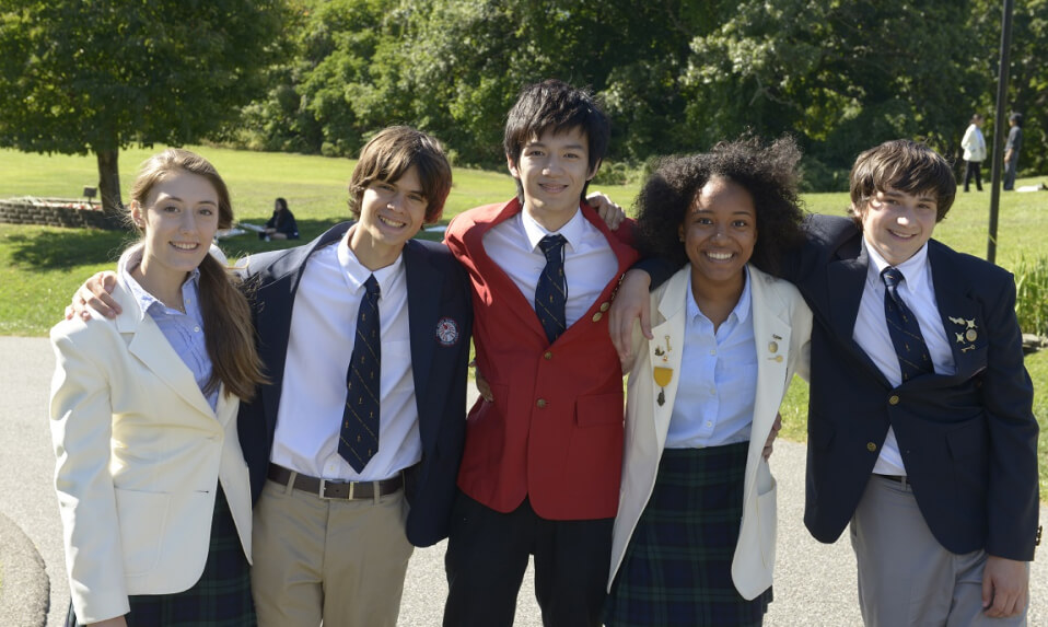 Knox School students dressed in blazers standing arm-in-arm and smiling for the camera.