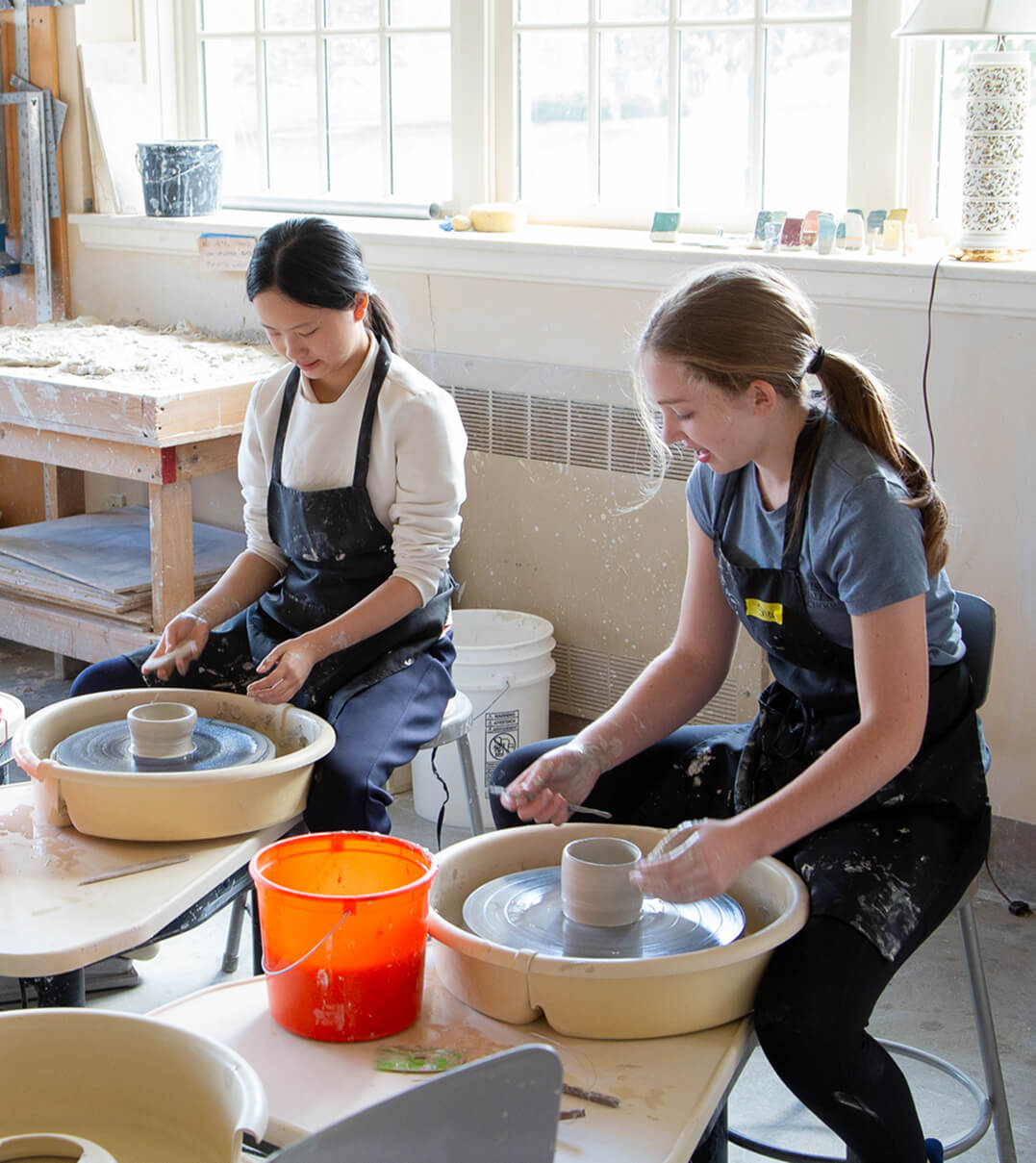 Two Miss Hall's School students working pottery wheels.