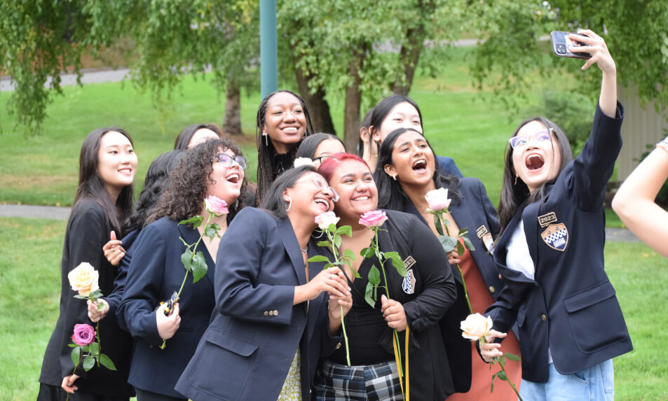 A group of international Miss Hall's School students holding roses and taking a selfie.