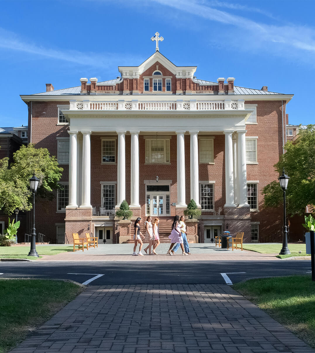 Students walk in front of a historic campus building