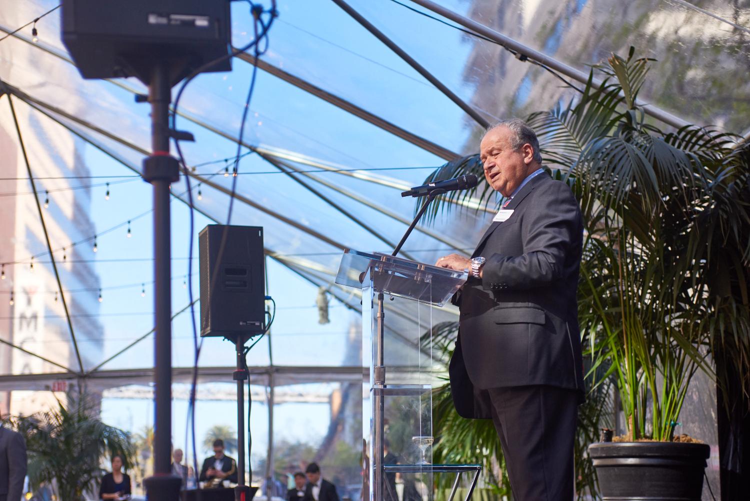 Speaker at a garden podium under a clear-top tent