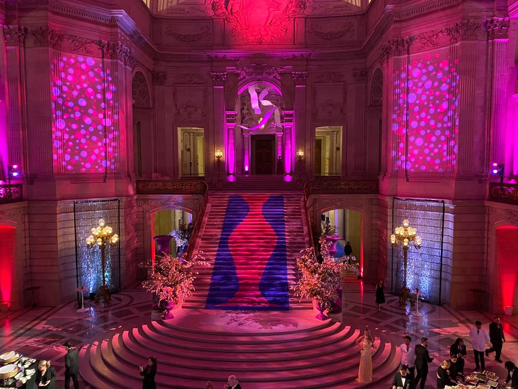 A grand staircase washed in deep magenta light at a Bay Area gala
