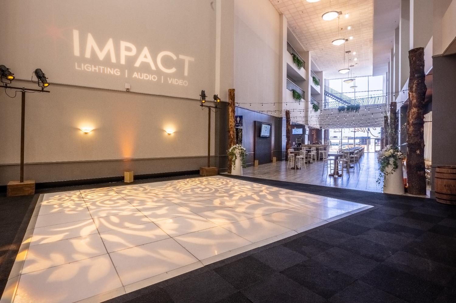 Impact logo projected in light across a lobby floor
