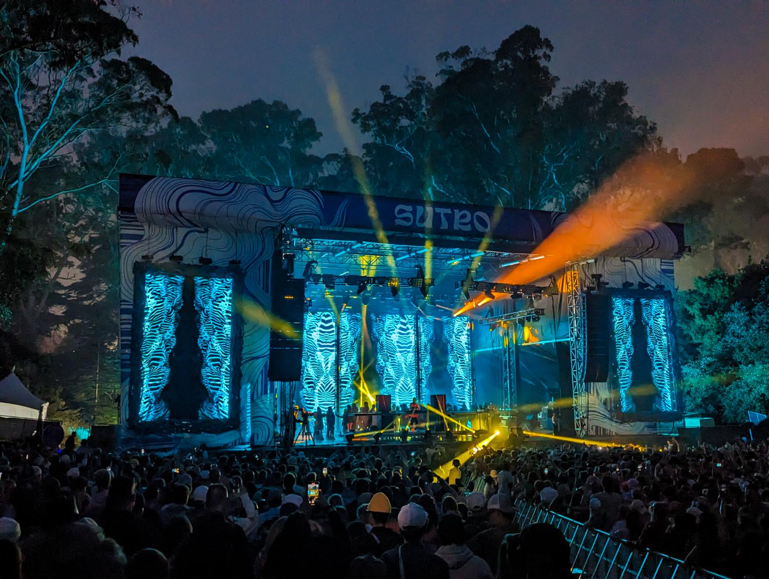 Outdoor festival stage with teal beams over the crowd