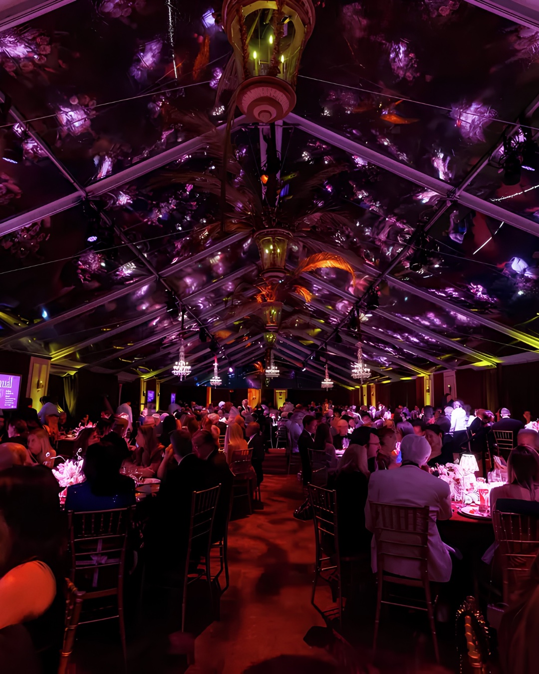 Gala dinner beneath a tent ceiling projected with violet floral gobos and crystal chandeliers at the de Young