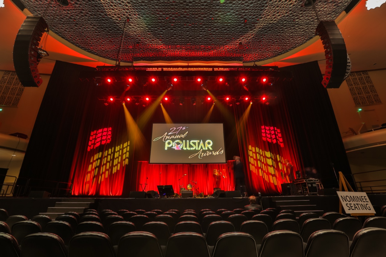 A symmetric red-lit awards stage with aerial beam lighting and the Pollstar Awards screen at The Masonic, produced by Impact.