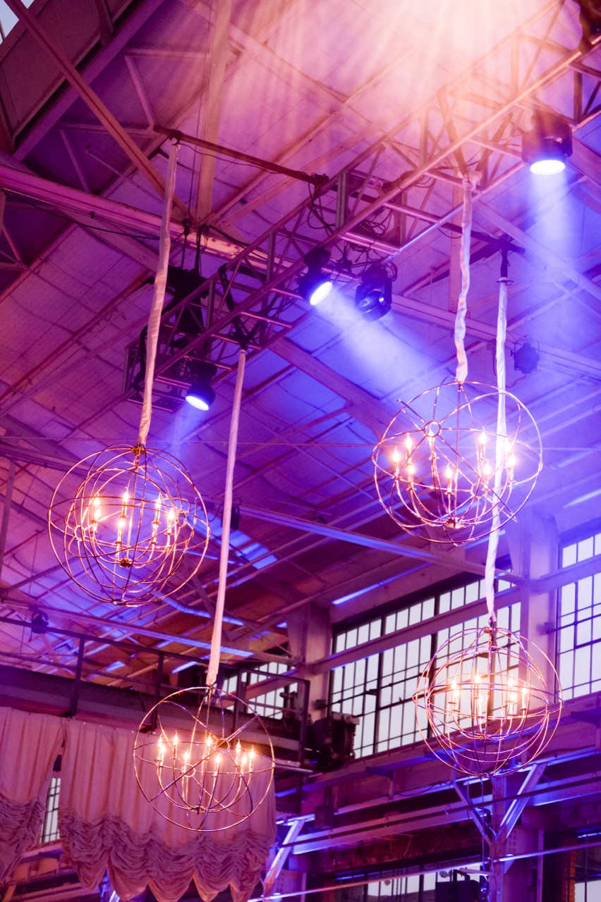 Impact's orbital sphere chandeliers and blue spotlight beams hang from the industrial truss at Craneway Pavilion.