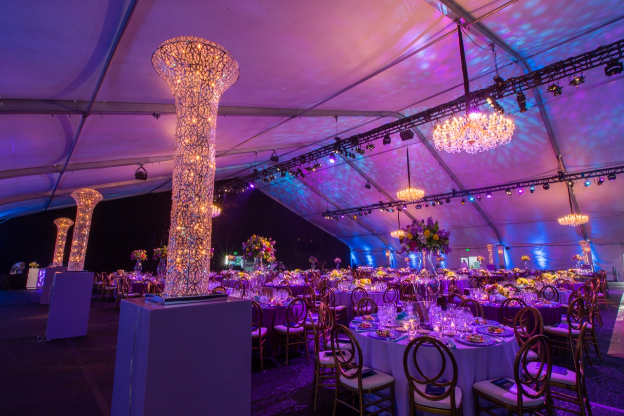 Impact's crystal chandeliers, illuminated mesh columns, and purple uplighting fill a tented gala at Menlo Circus Club.