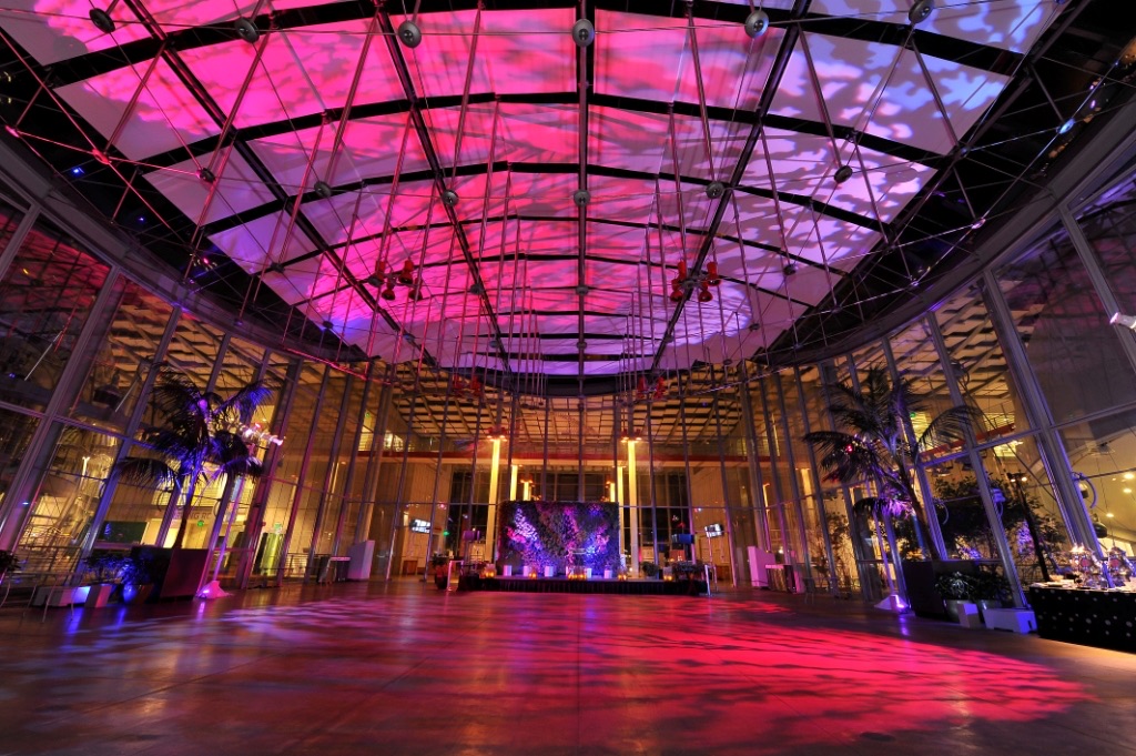 Impact bathes the glass-domed piazza at the California Academy of Sciences in magenta and pink uplighting with a cloud gobo wash across the ceiling above an open dance floor.