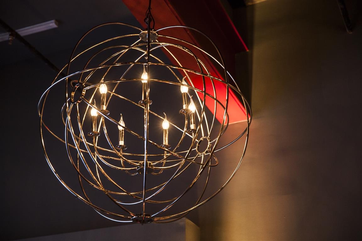 A spherical orbit chandelier hangs illuminated over a corporate event space lit by Impact.