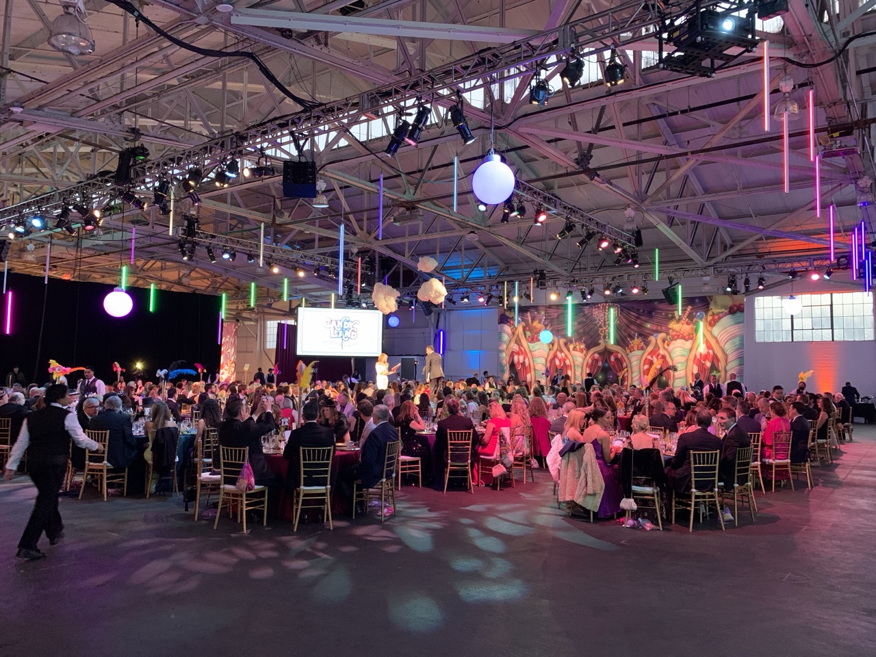 Impact's truss-mounted moving lights and LED tube accents illuminate a packed gala crowd in the Fort Mason pavilion.