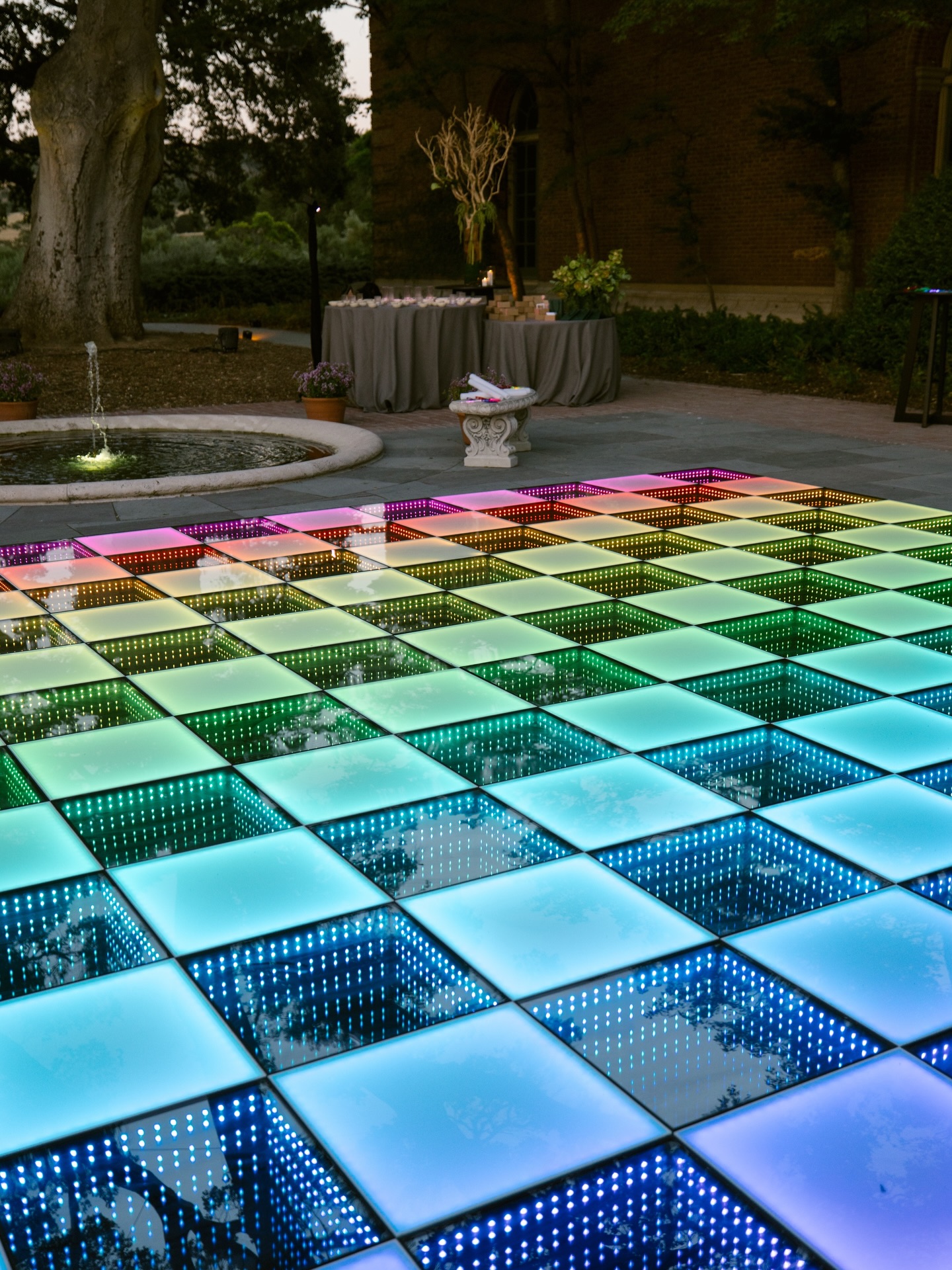 Rainbow infinity dance floor set beside a garden fountain at an outdoor Bay Area event