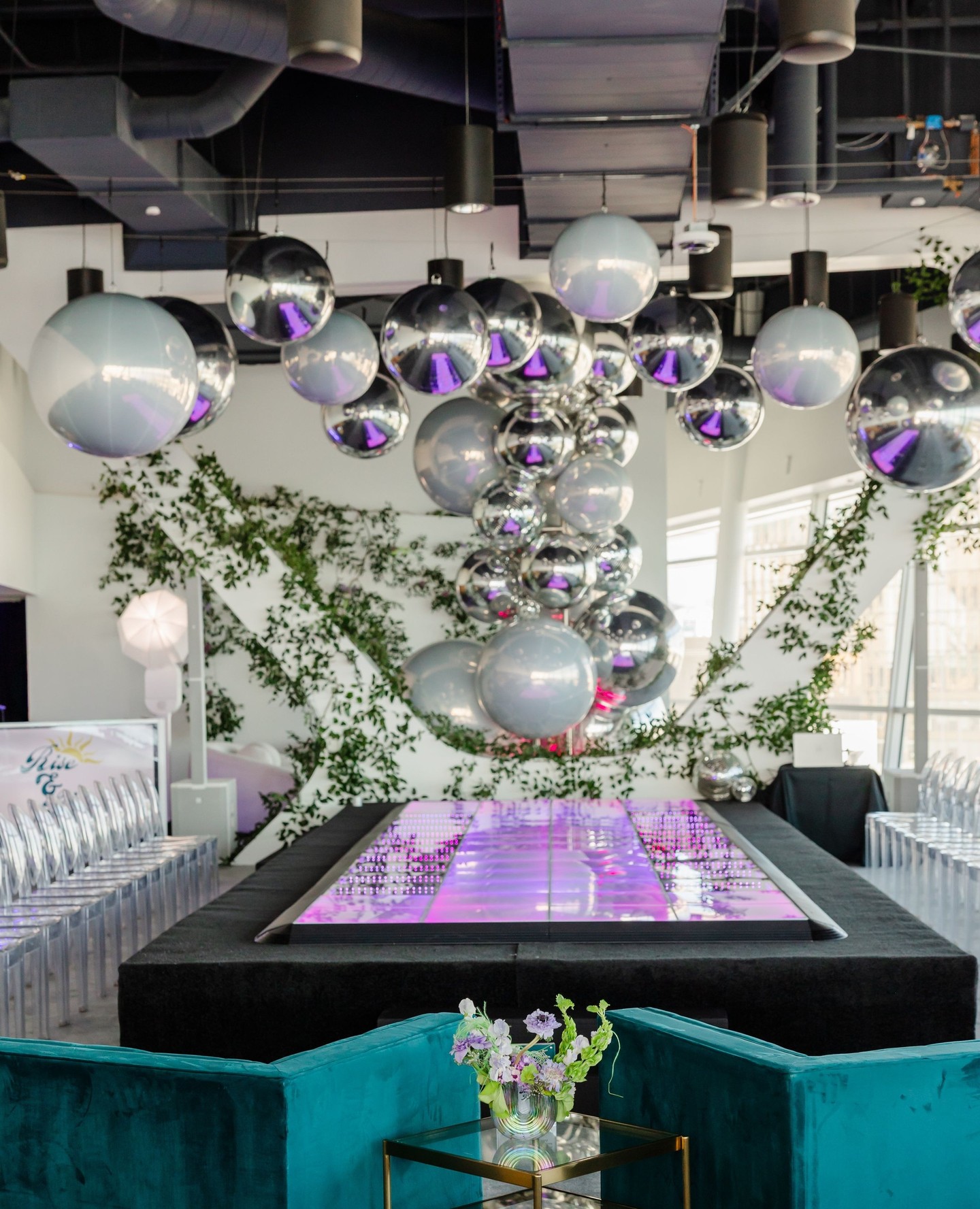 Elevated runway built from infinity dance floor panels beneath silver spheres and greenery
