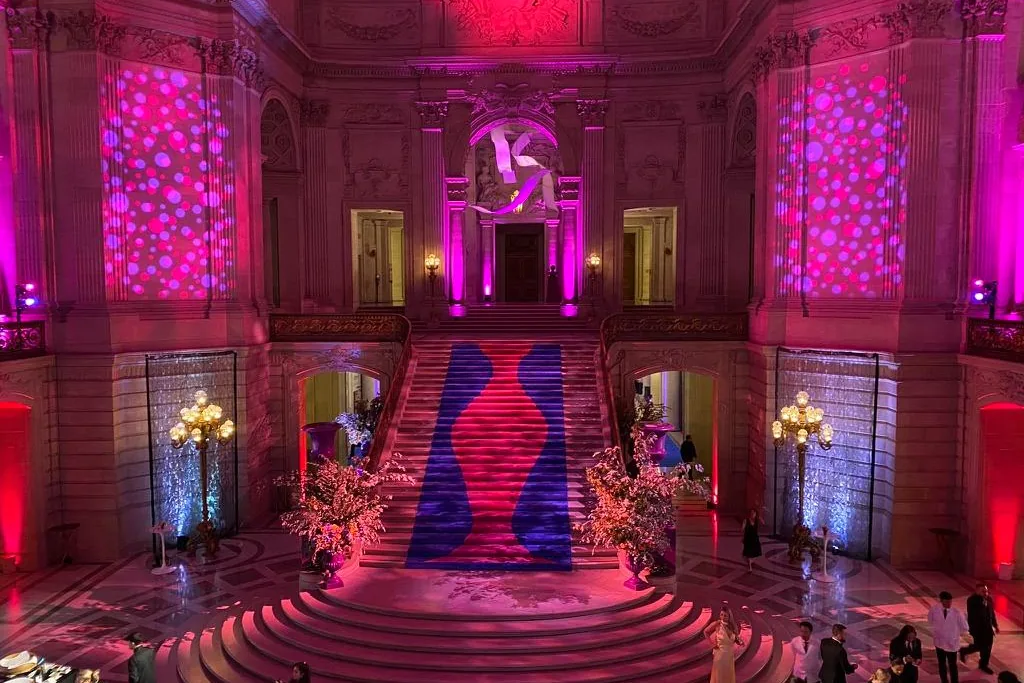 A grand staircase washed in deep magenta light at a Bay Area gala