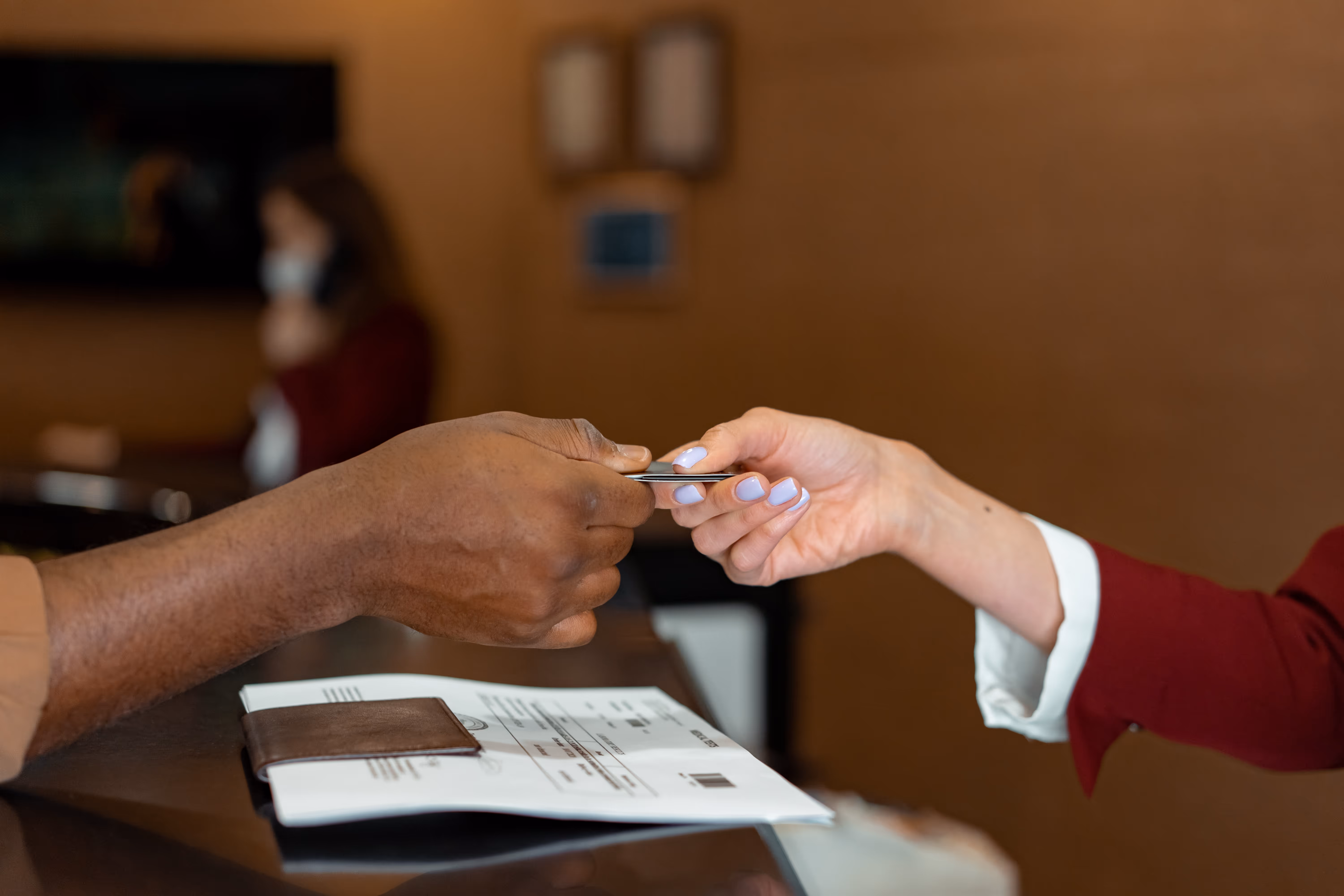 one person handing off a card to another at the reception desk of a hotel 