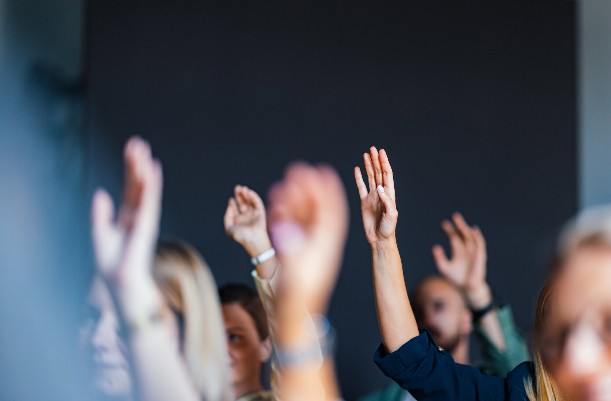 Hands raised during a discussion, representing retailer decisions about Deposit Return Scheme fees