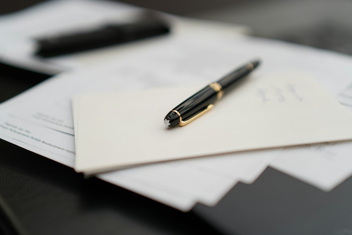 Un stylo posé sur une pile de documents, évoquant le contrat de location écrit qui fixe la date de fin du séjour.