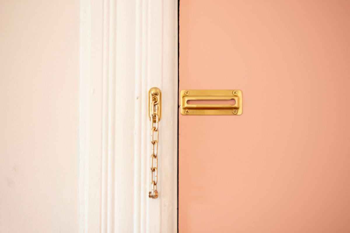 Une chaîne de sûreté dorée sur une porte d'entrée, symbole de la sécurité du logement loué.