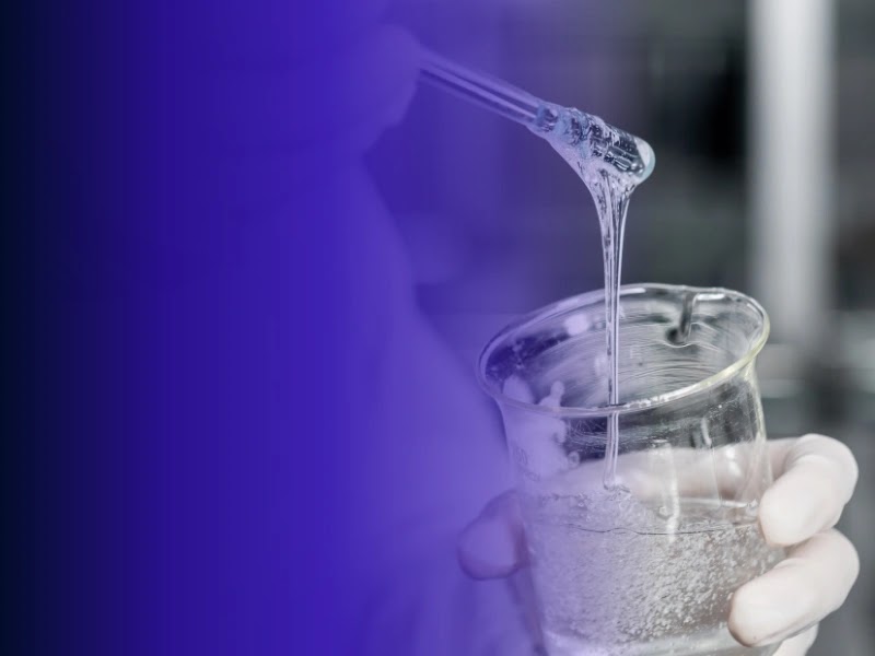 A scientist examines a viscous formulation sample above a glass beaker.