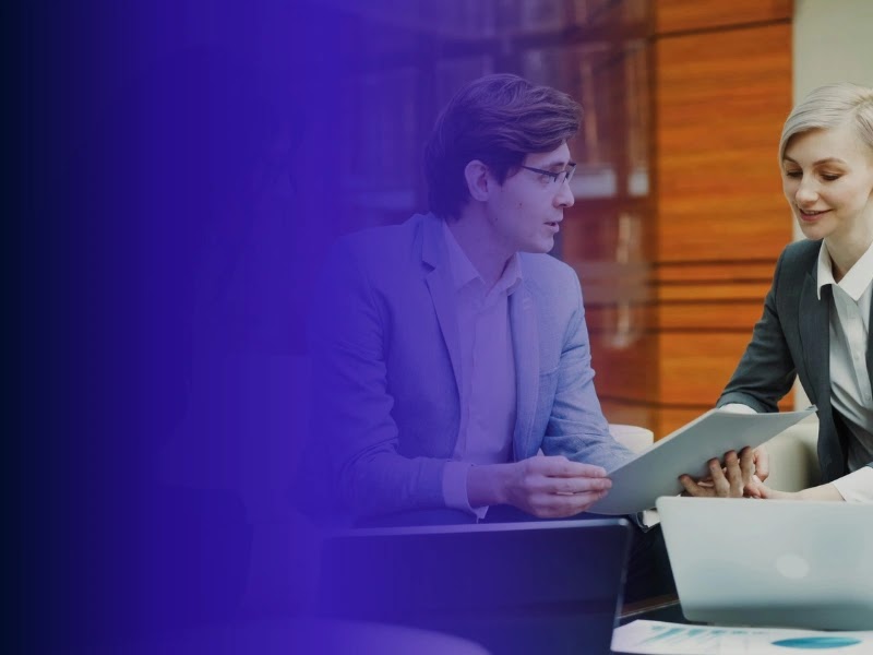Two colleagues review product-development plans at a laptop.