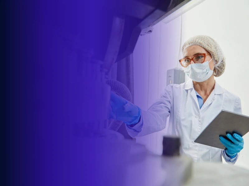A scientist in protective laboratory clothing reviews research records.