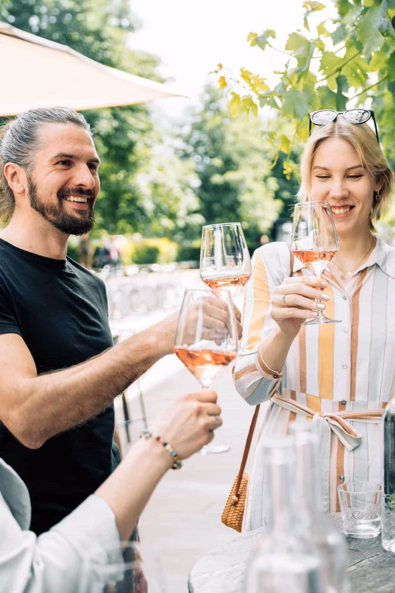 Three people clinking glasses of rosé wine in Ljubljana Central Market.