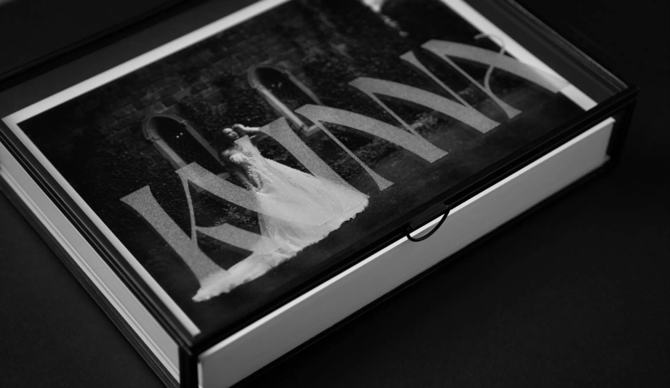 Kvinna Studio luxury photo album in black display box with acrylic lid showing a black and white bridal portrait overlaid with the Kvinna wordmark, brand design by Unbound Collective